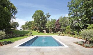 swimming pool on a large patio in a garden