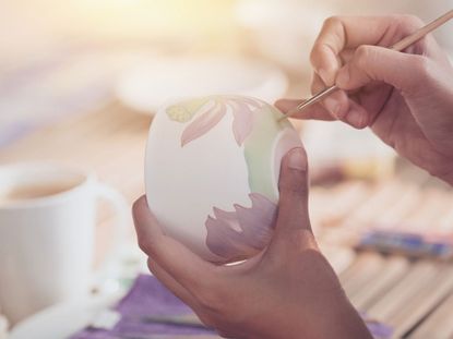 Person Painting Flowers On Pottery