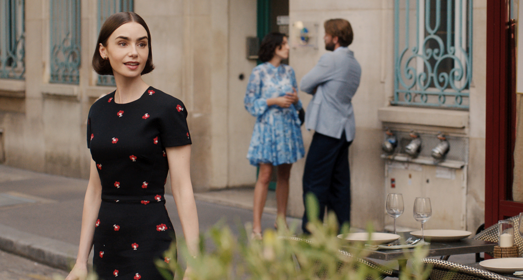 lily collins as emily wearing a black and red polka dot dress turning around her shoulder surprised on a european street in season 5 of emily in paris