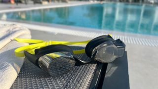 FORM Smart Swim 2 swimming goggles next to an outdoor pool