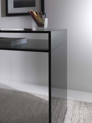 The 'Bristol' desk was designed in-house by the Coedition Studio. Black desk made of black tinted glass with a storage shelf.
