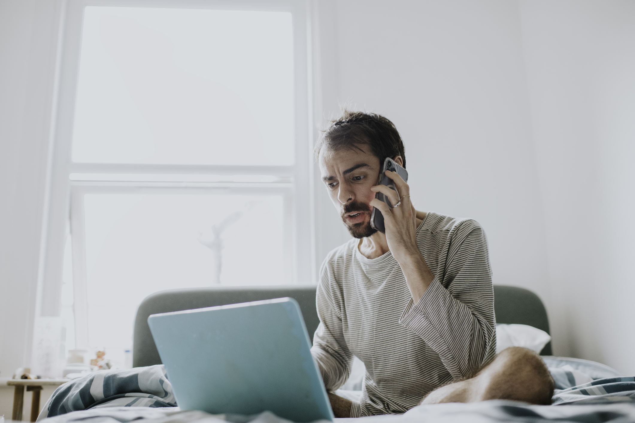 Concerned man looking at laptop while on the phone