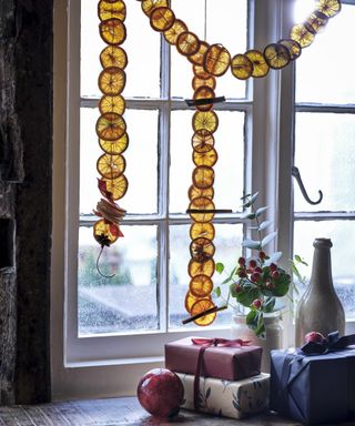Window with wrapped gifts on sill and orange slice garland