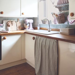 A kitchen with a gingham curtain covering the under-sink storage area
