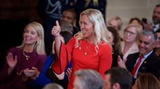 Marjorie Taylor Greene, in a red dress, giving Donald Trump a thumbs up