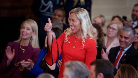 Marjorie Taylor Greene, in a red dress, giving Donald Trump a thumbs up