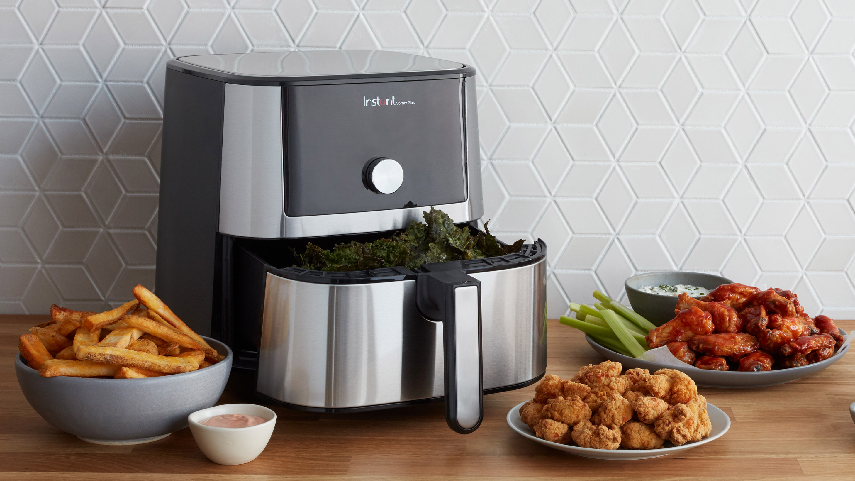 Instant Vortex Plus on a countertop surrounded by food cooked in the air fryer