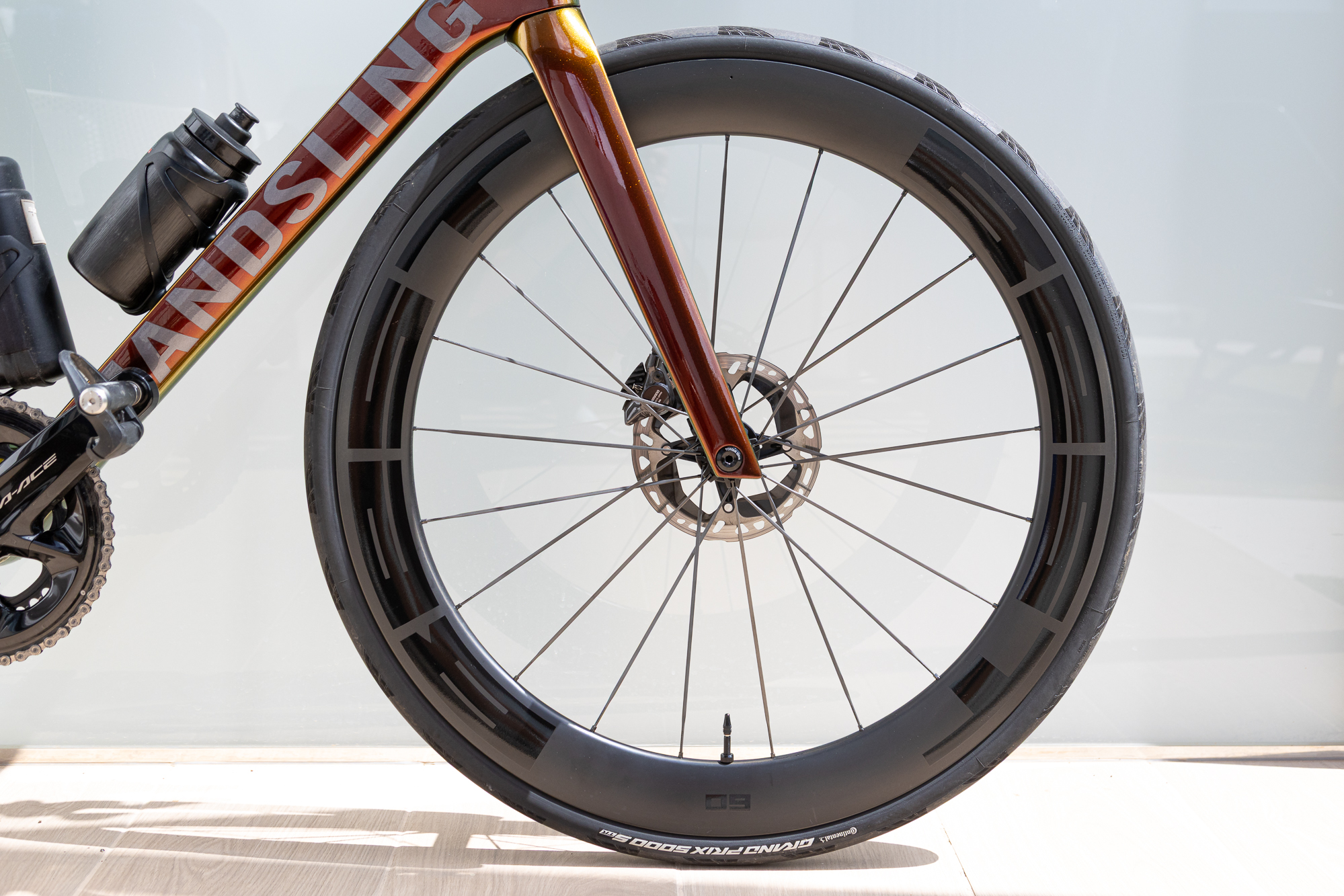 close up of a carbon front wheel and orange frame of a road bike