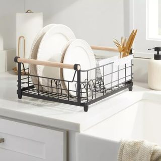 A black metal dish rack with wooden handles, stacked with white dinnerplates