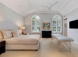 A secondary bedroom with beige carpet, beige bed and a large table