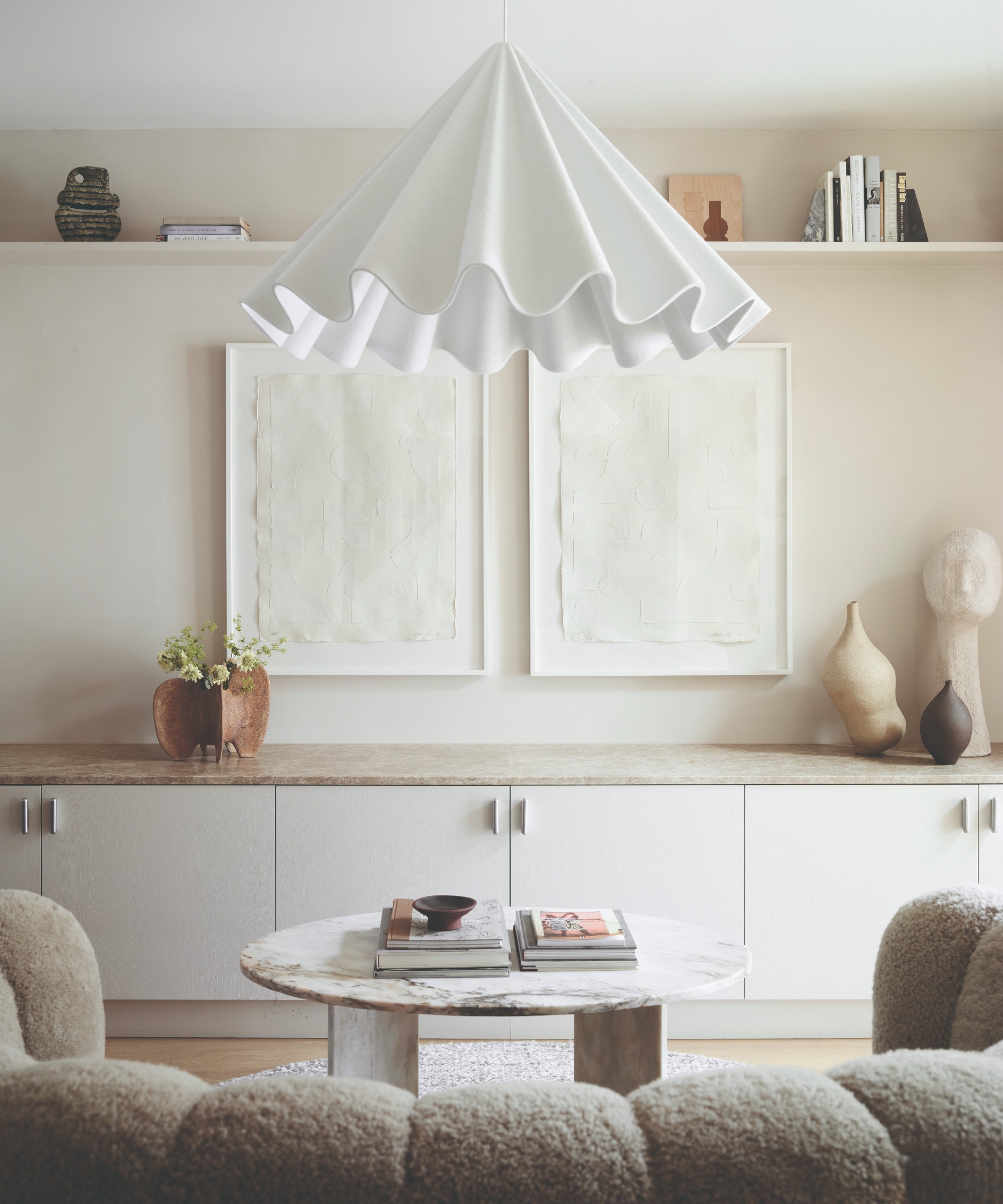 A white living room with a curved boucle sofa and a round marble coffee table