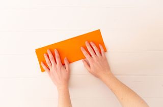 Hands folding a piece of paper in half.