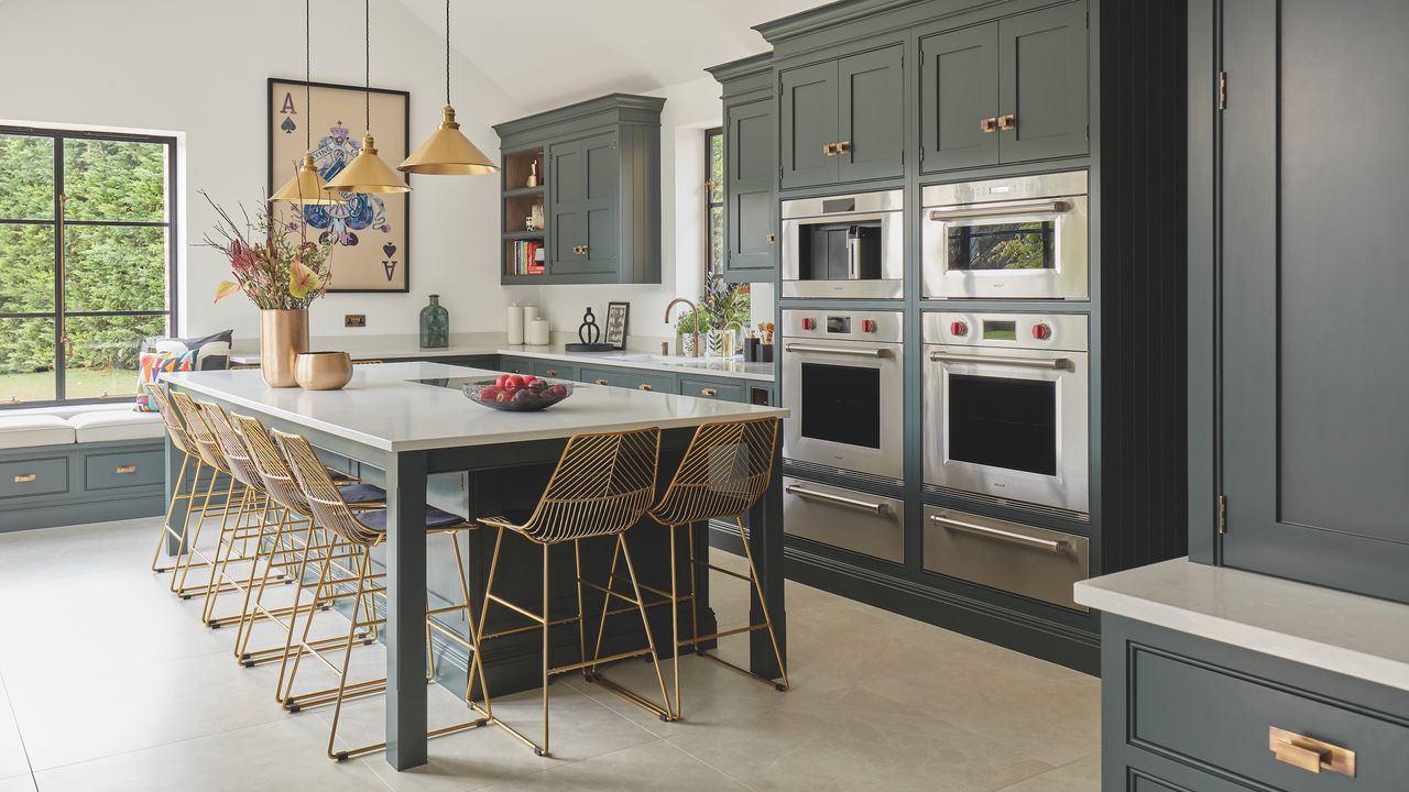 green kitchen with large island with gold pendants and bar stools