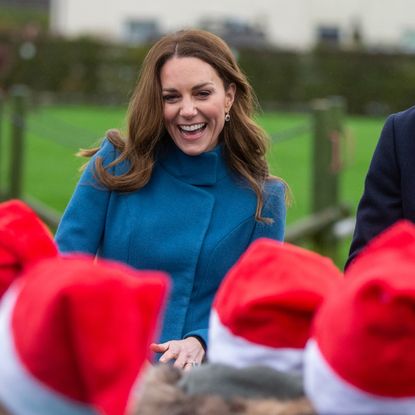 Kate Middleton wears a blue coat as she watches children wearing Santa hats alongside Prince William