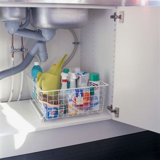 Under sink wire storage basket filled with cleaning products