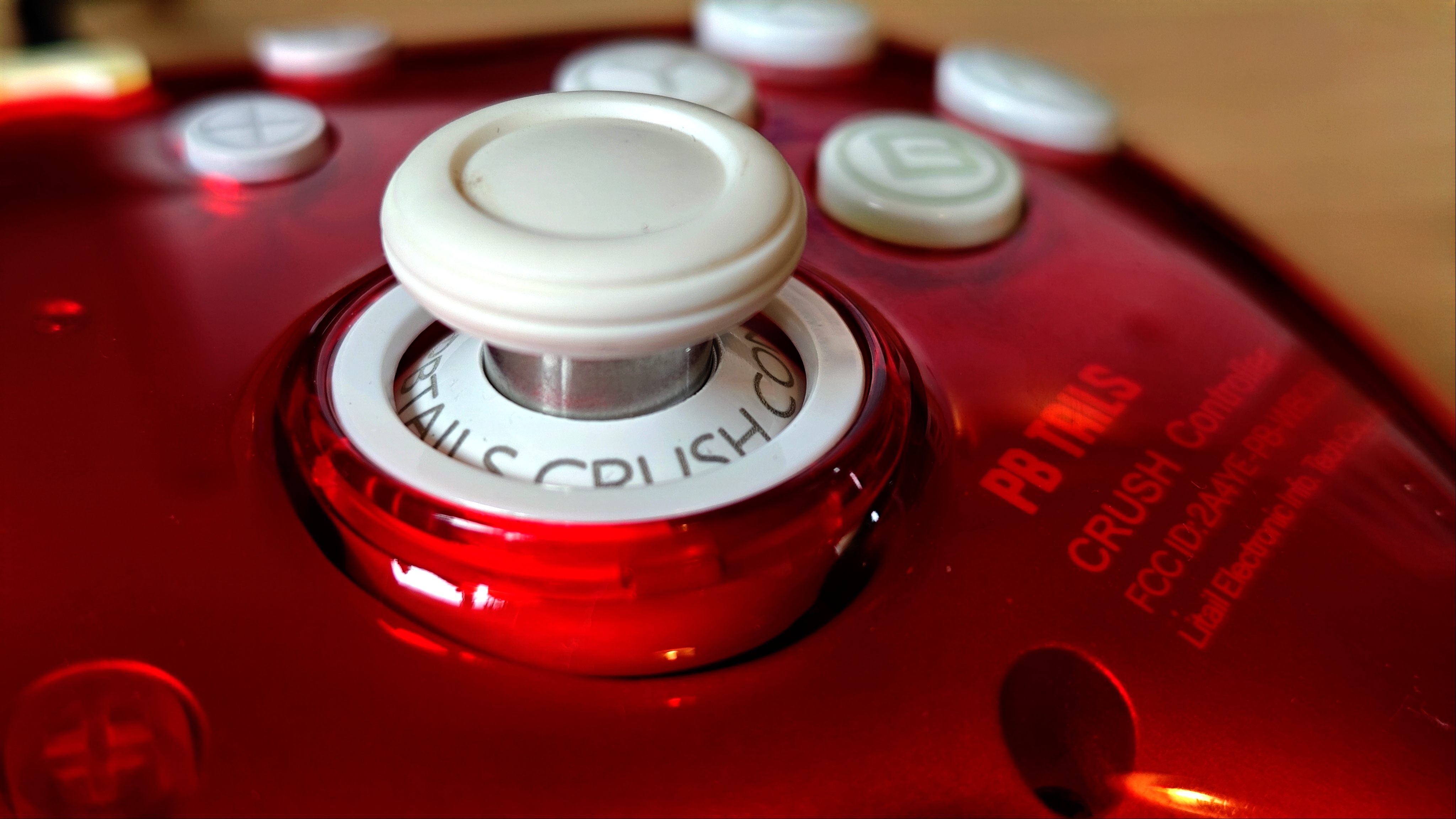 A Ruby red PB Tails Crush gaming controller sitting on a wooden desk