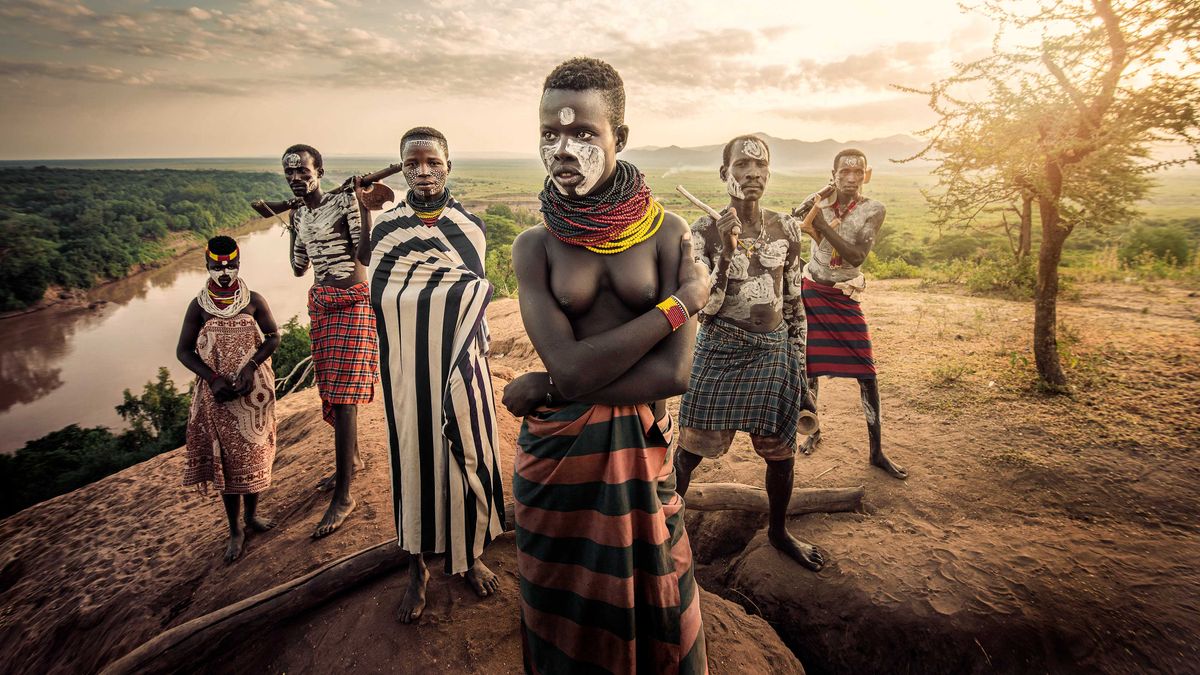 Tribal Africans stood on a mound above river