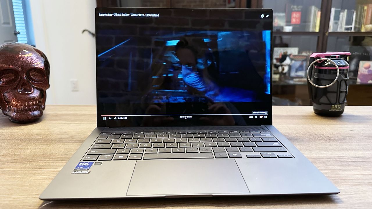 Asus Zenbook S 14 resting on a wooden desk showing a dark game on its display.