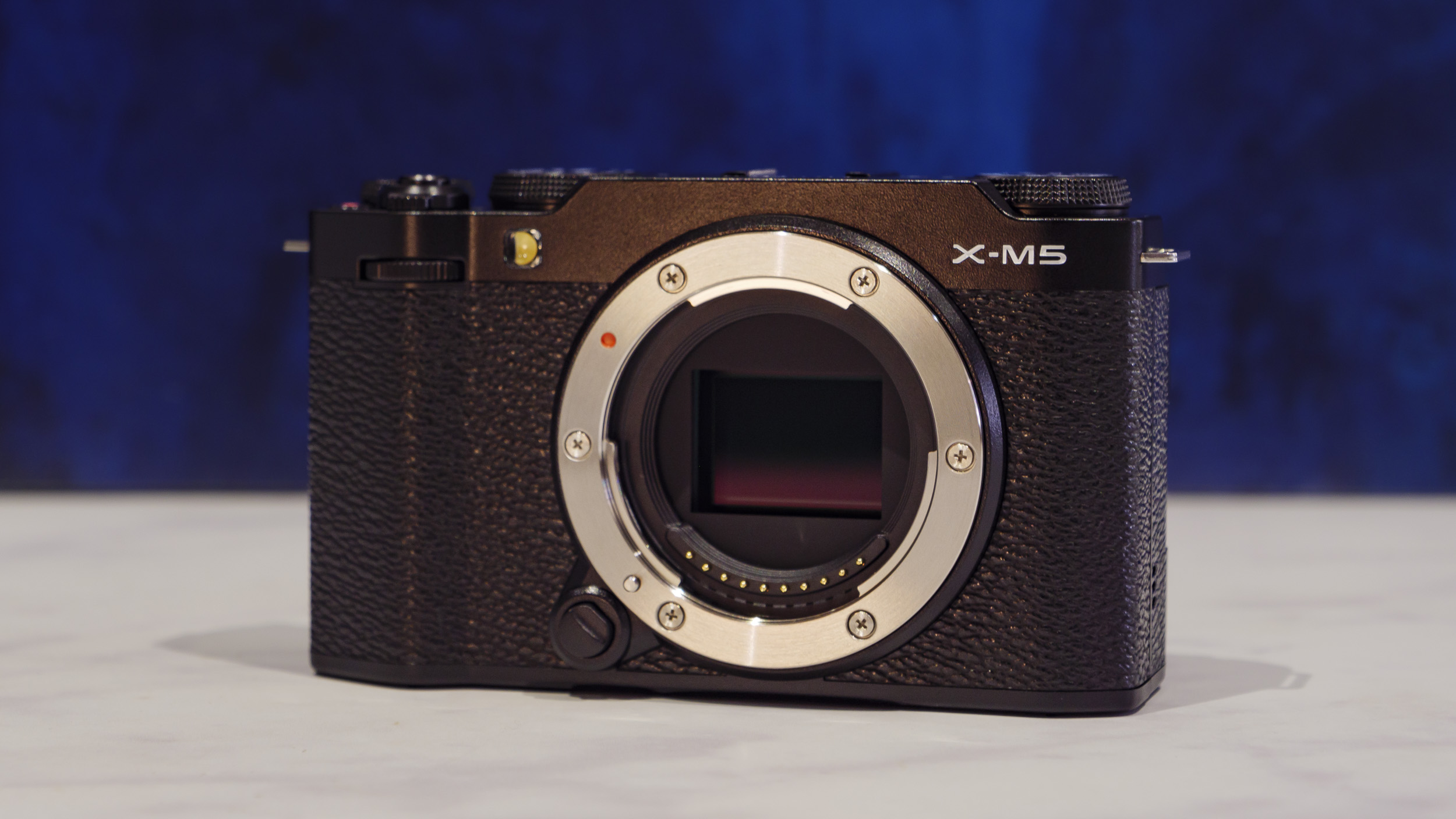 Fujifilm X-M5 camera on a marble surface with rich blue background