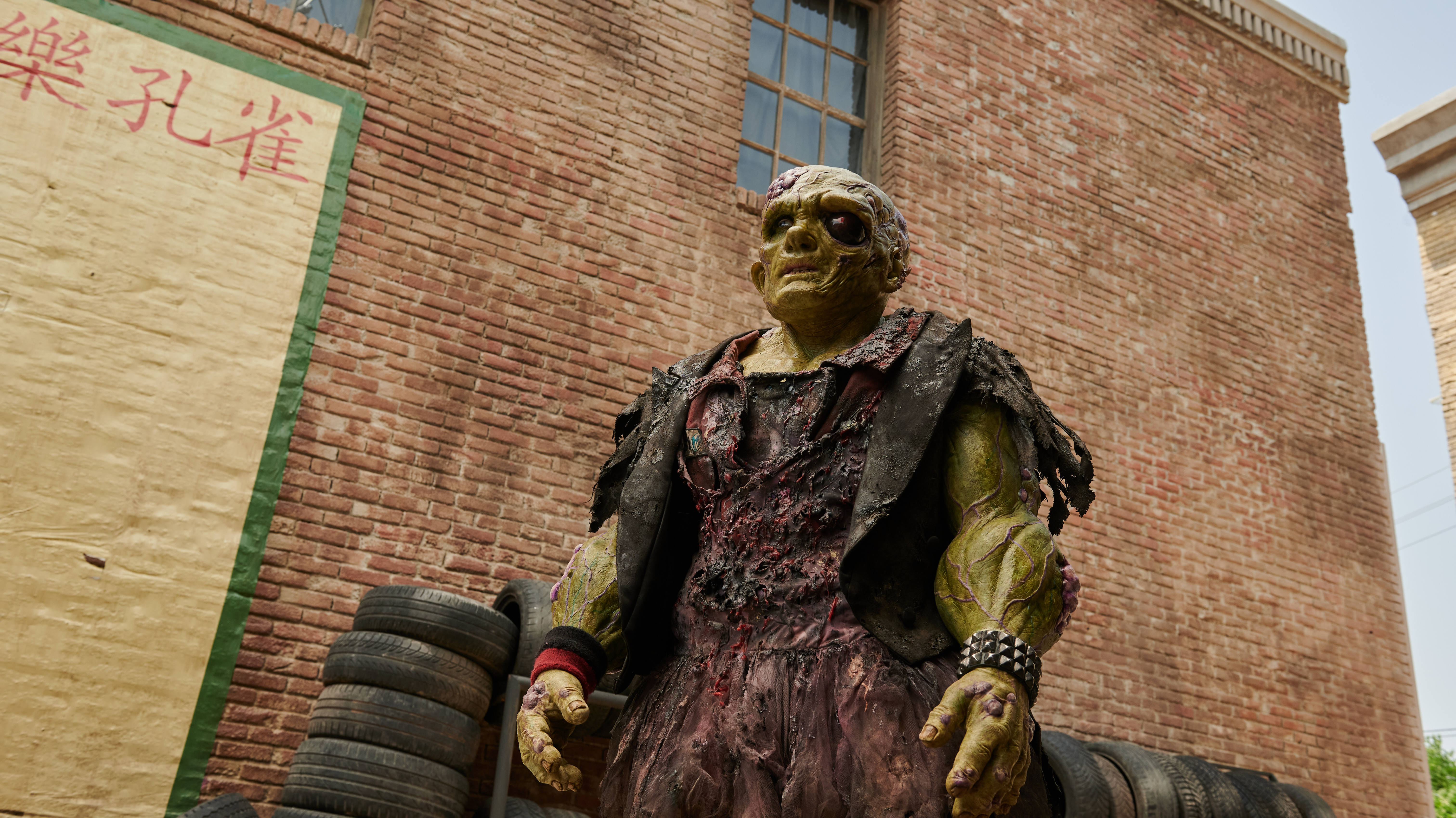 a green monster walking down an alley in a still from the movie the toxic avenger