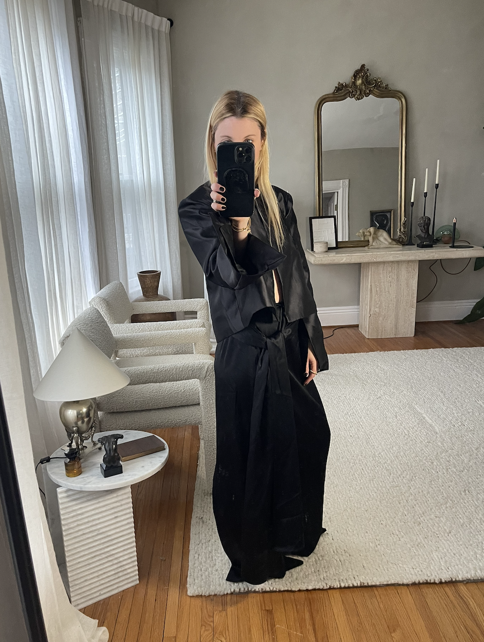 Kerri Pieri in a black satin jacket and black silks skirt mirror selfie