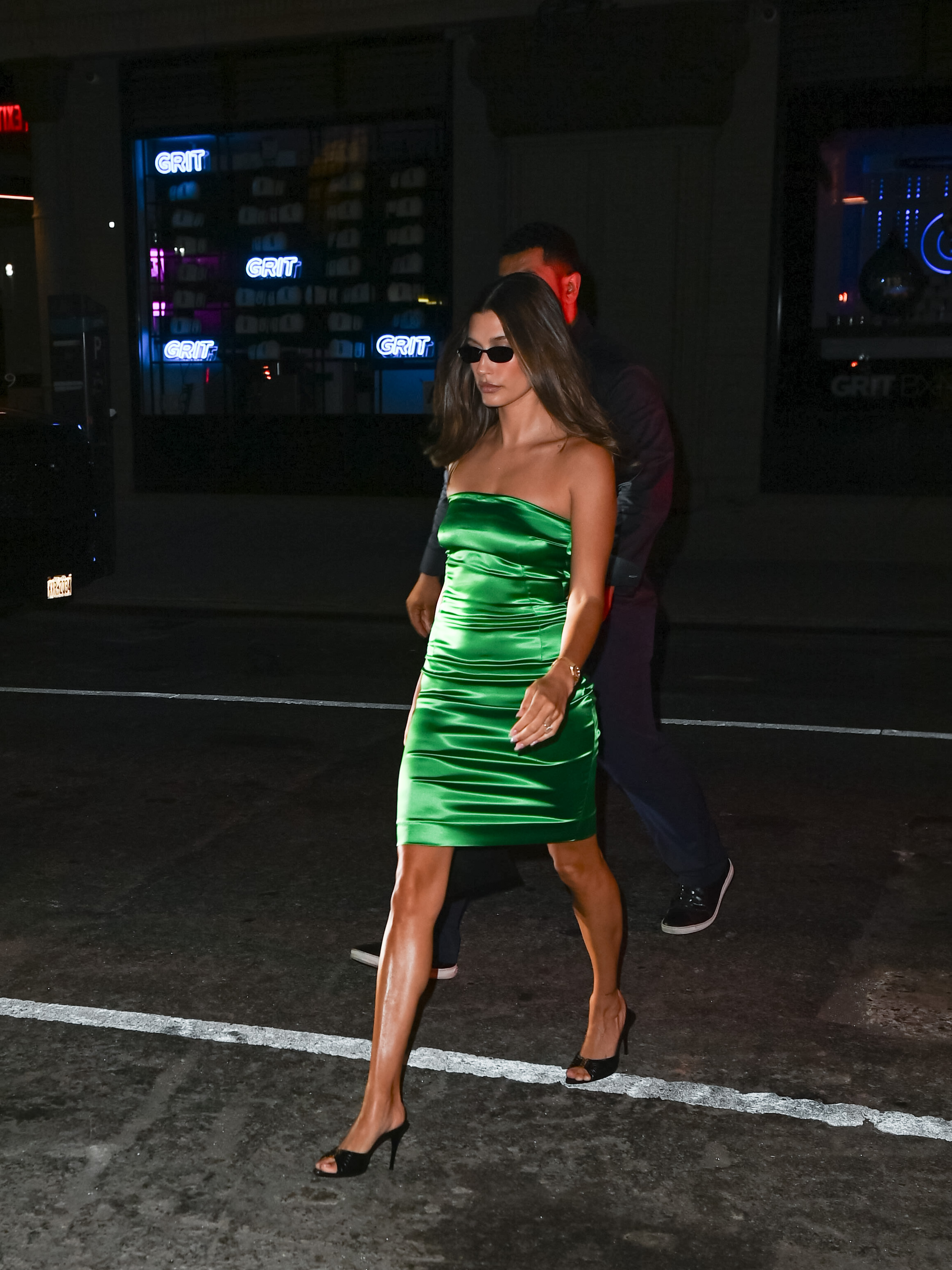 Hailey bieber wears a green mini dress, and black mules.