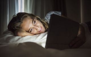 Woman in bed looking a tablet screen