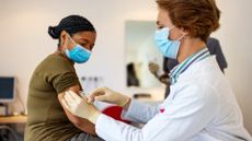 A medical professional giving a woman a vaccine.