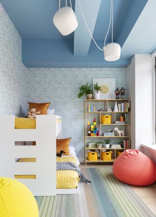 A kids bedroom with blue ceiling, wallpaper and a bunk bed