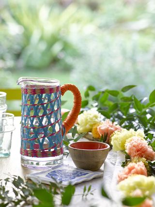 colourful jute jug ans decorative flowers on an outdoor dining area
