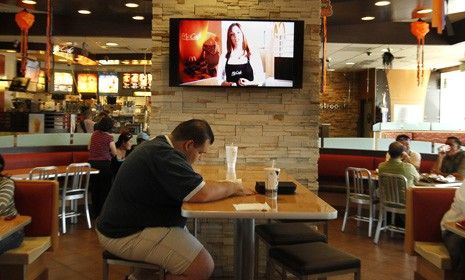 A customer sits at a table near an HDTV screen playing McDonald&amp;#039;s new TV channel, which is being tested in California before a national rollout.