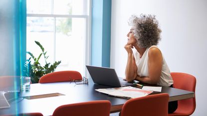 Woman sitting at a desk wondering.