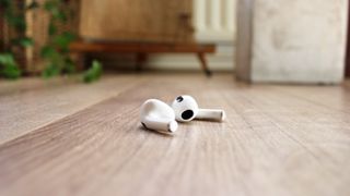 Apple Airpods 3 liggende på et gulv.