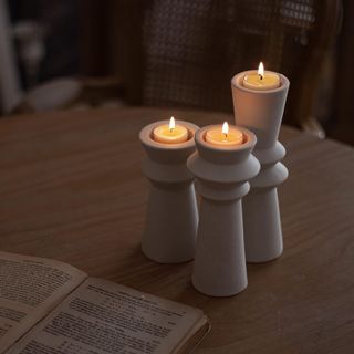 three matte white stoneware tall candle holders with a ridged pillar design