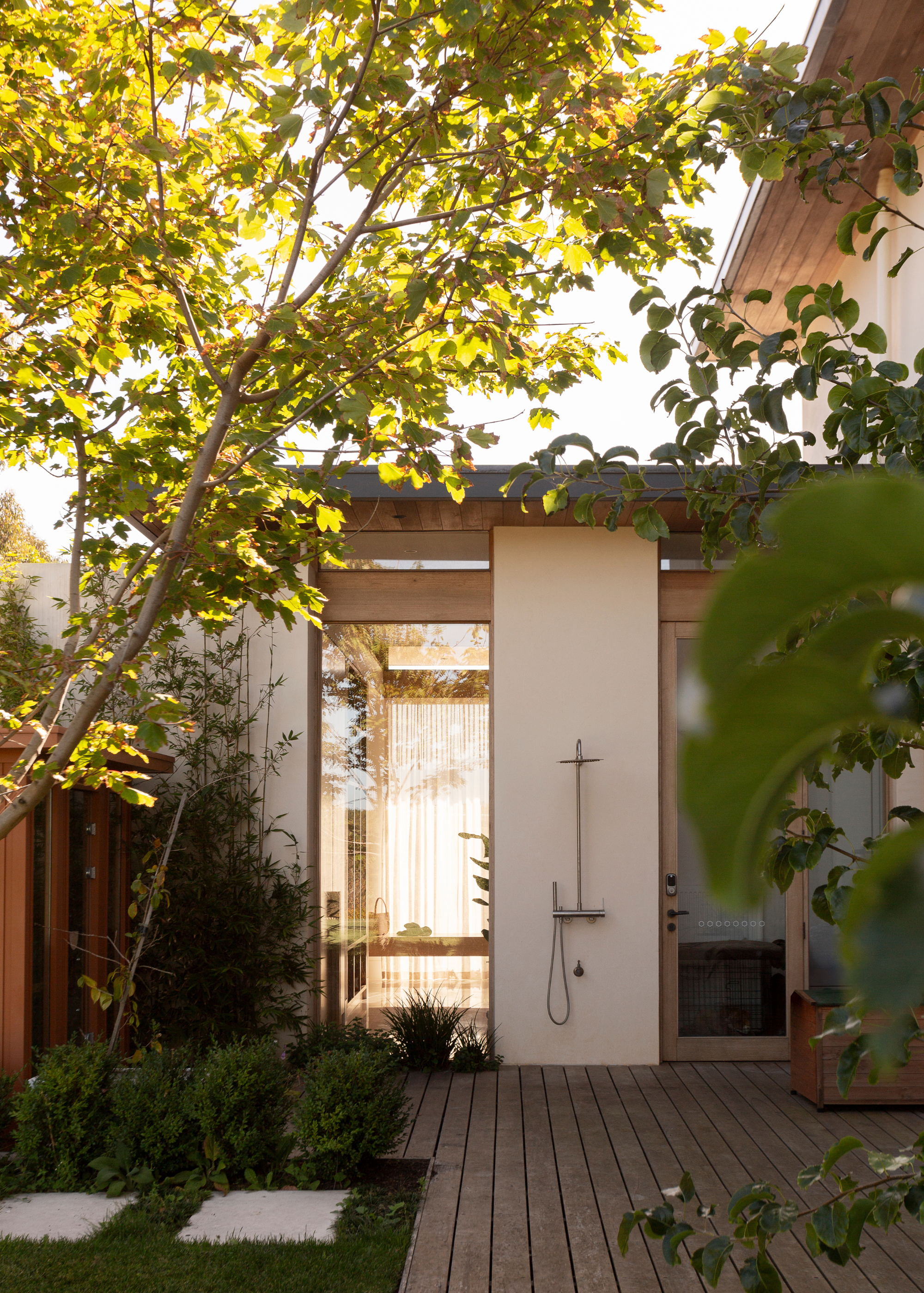 An outdoor shower with trees around it outside of a home
