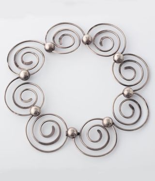 Silver spiral necklace against a grey backround.