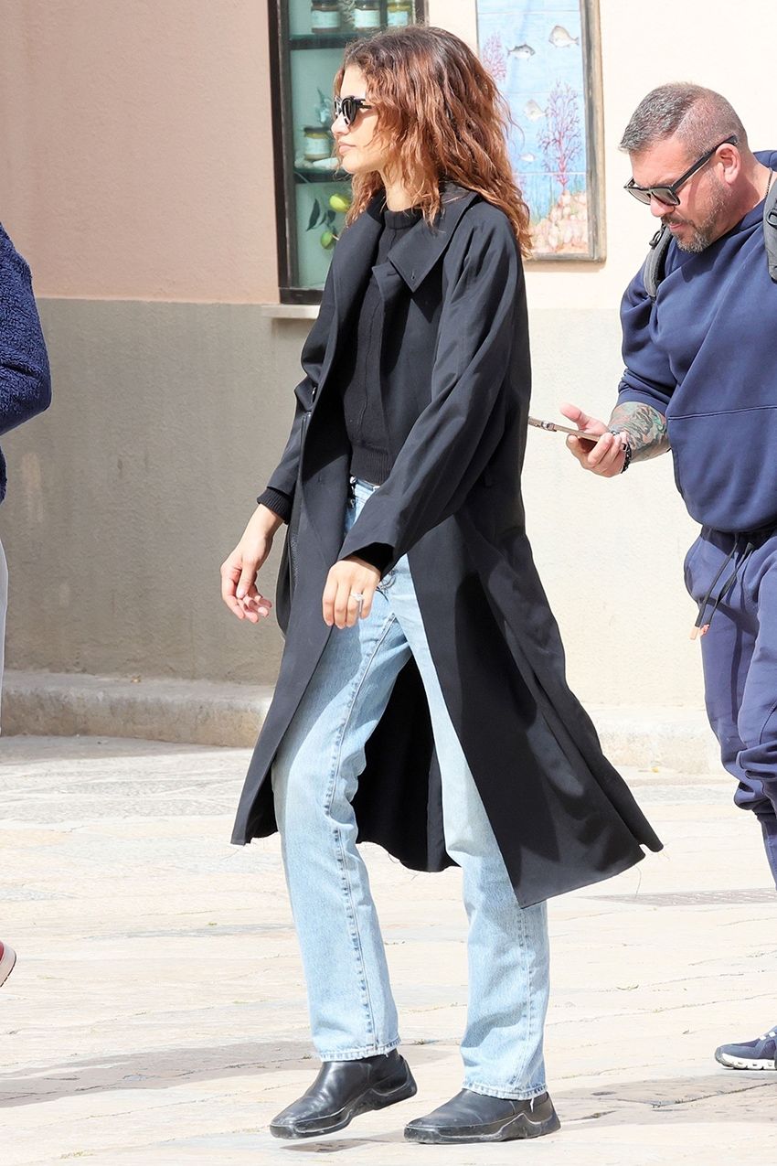 Zendaya wearing a black trench and light-wash jeans in Italy
