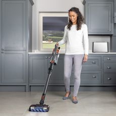 A woman using a Shark IZ300UK to clean a kitchen floor