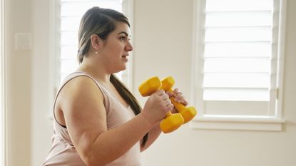 Woman exercising with dumbbells at home