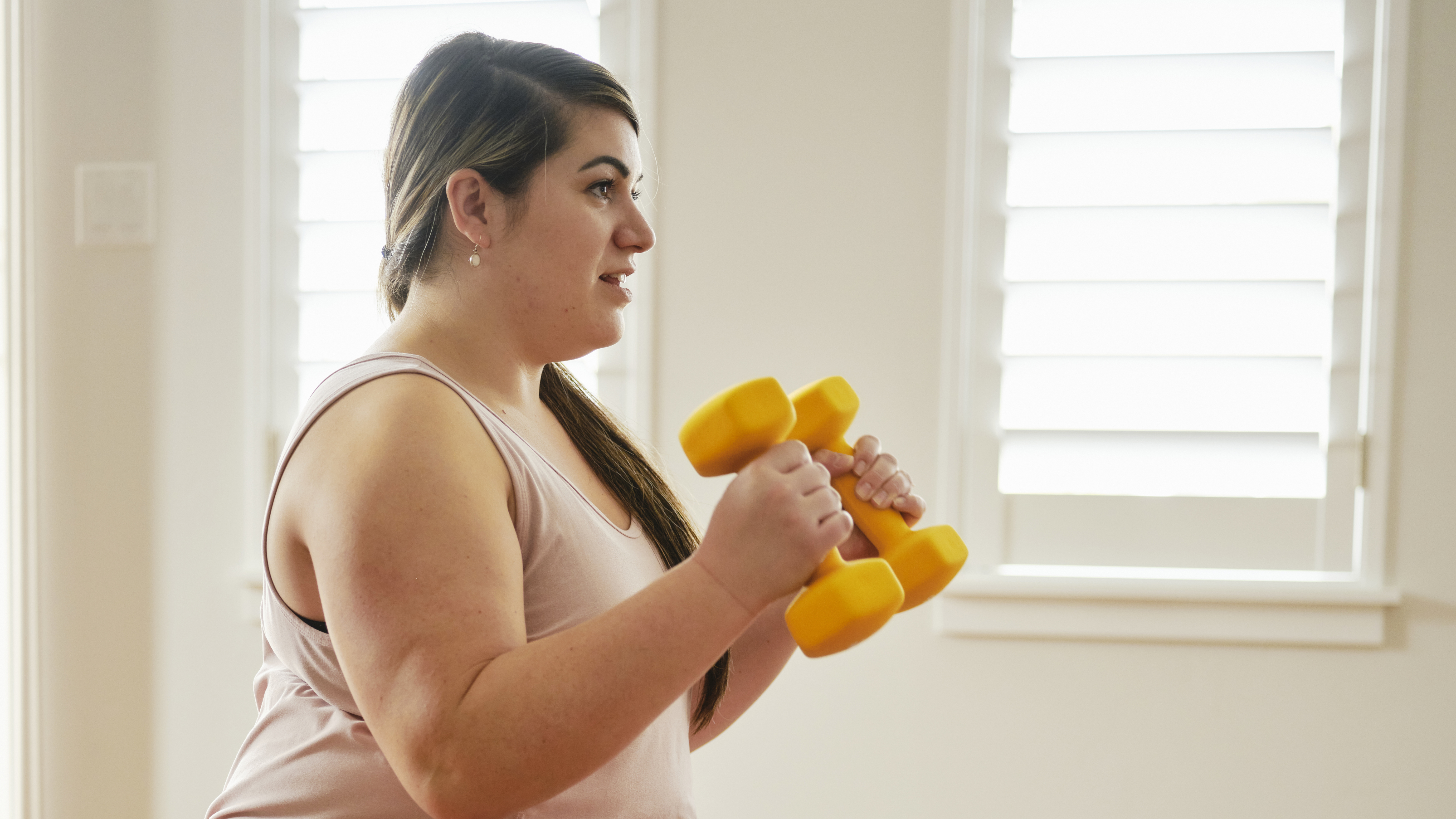 Woman exercising with dumbbells at home