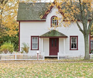 A Fall lawn with fallen orange leaves in front of a house