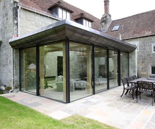 modern glass extension with aluminium curved roof attached to older stone building