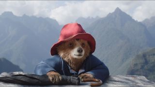 Paddington holding an umbrella after climbing a cliff in Paddington in Peru