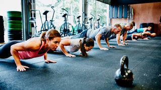 Row of people doing push-ups in gym