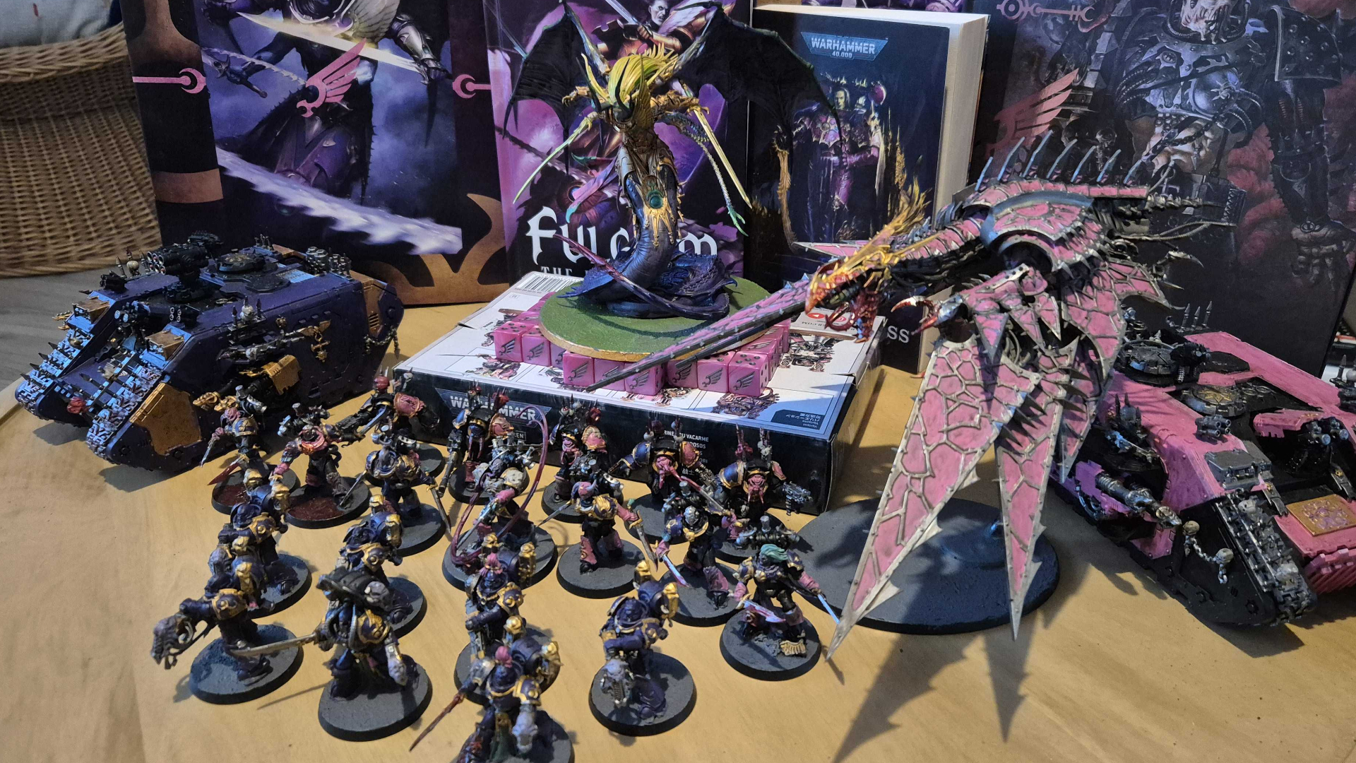 Emperor&#039;s Children models and vehicles alongside books and boxes on a wooden surface