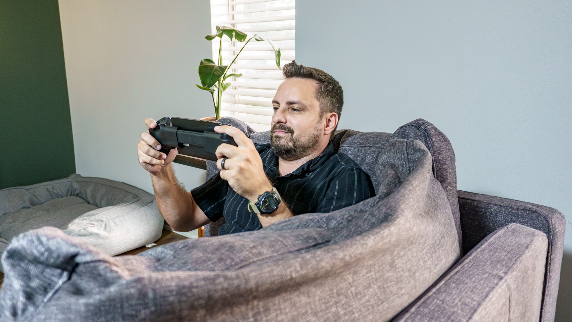 A person sitting on the couch playing games using the Elo Vagabond mobile game controller
