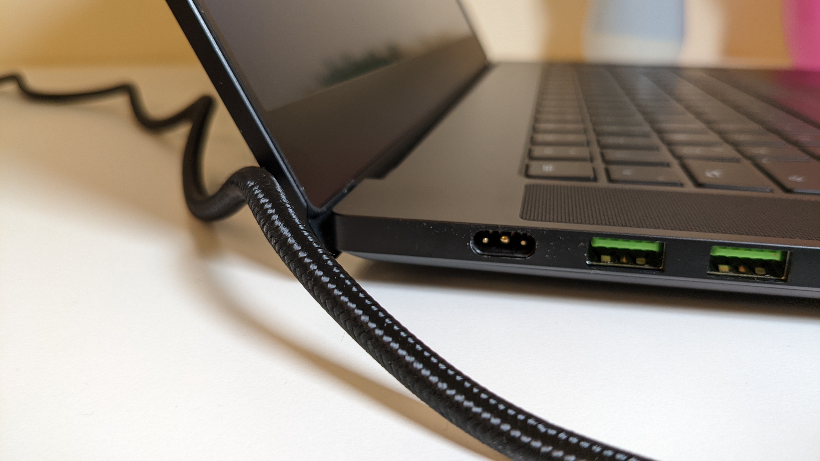 Nahaufnahme der linken Anschlussseite des Razer Blade 15 Advanced mit gewobenem Kabelmantel des Netzteils im Bild