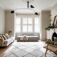 A spacious living room with a Berber-style rug, a cream sofa and a long ottoman