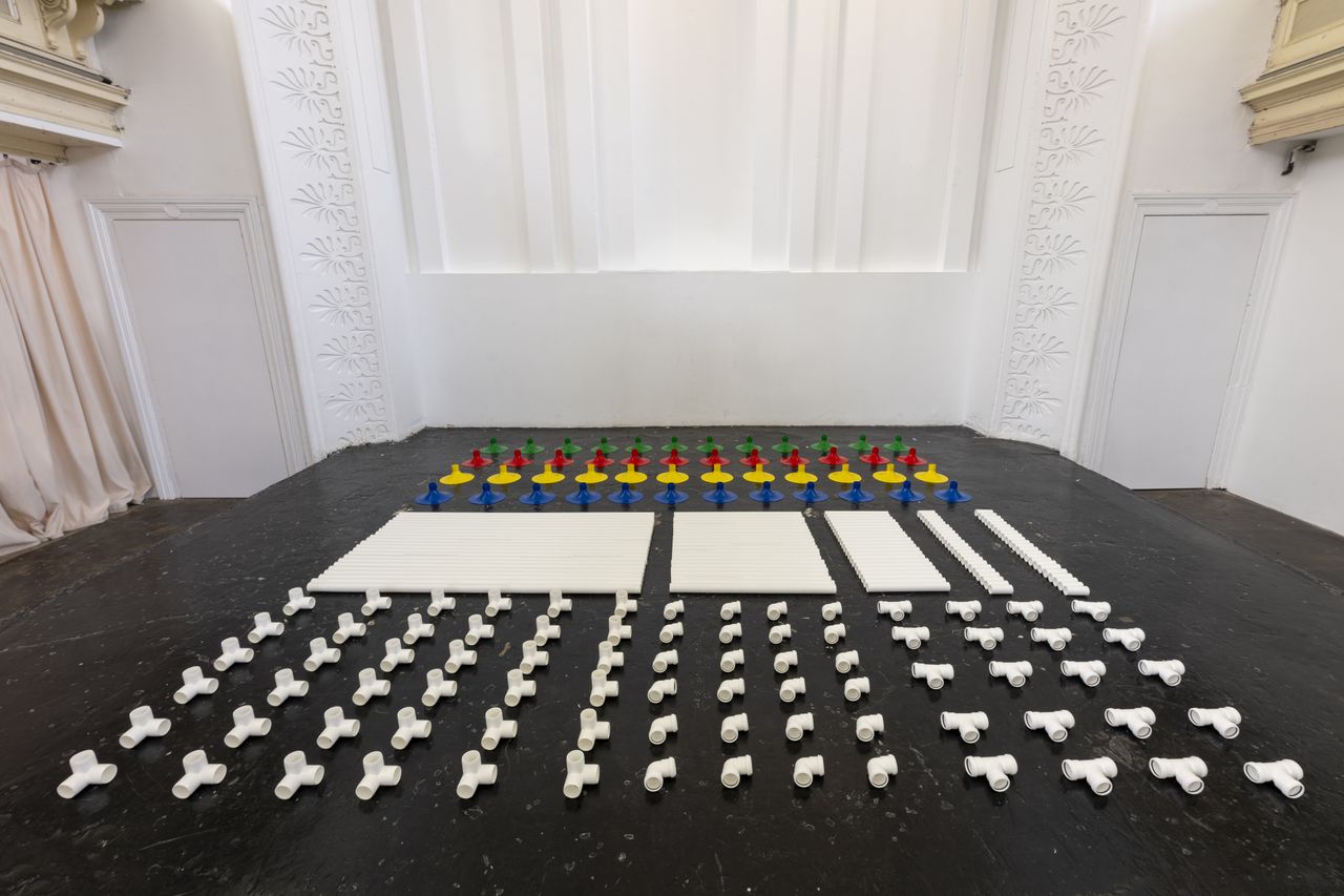 Installation in a former church made out of white pipes and colourful funnels