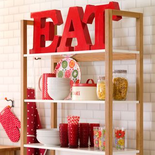 assortment of red and white kitchen crockery on wooden standalone display kitchen shelf